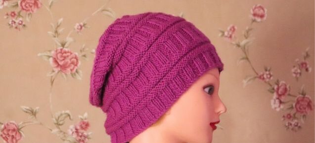 Unisex purple hat on a mannequin head, featuring Sunayana reversible hat pattern with a flourish background.