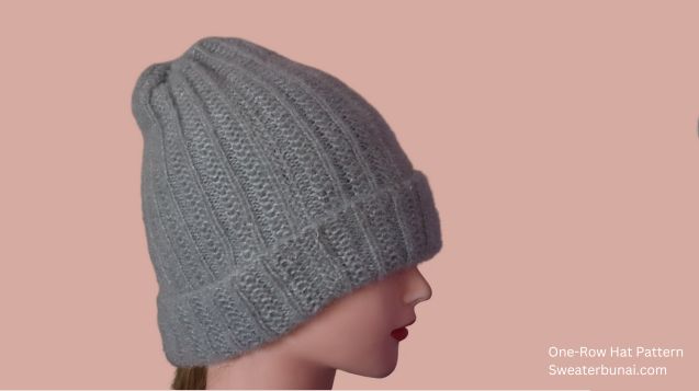 A woman mannequin wears a stylish gray knitted beanie, showcasing a one-row reversible beanie pattern against a contrasting background.