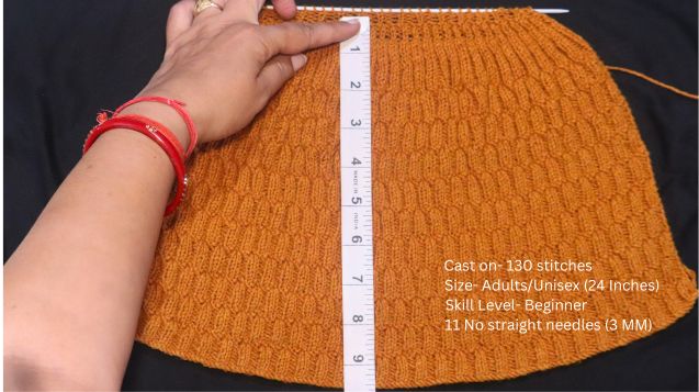 A person measuring the length of a knitted hat, referencing a Knit-Purl Stitch Hat Pattern Measurements guide.